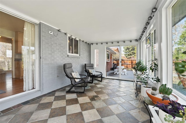 sunroom / solarium featuring stone tile floors and plenty of natural light