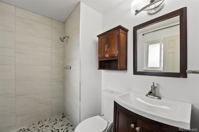 full bath with toilet, vanity, and tiled shower