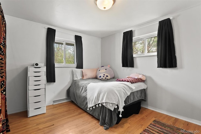 bedroom with baseboards, multiple windows, and light wood finished floors