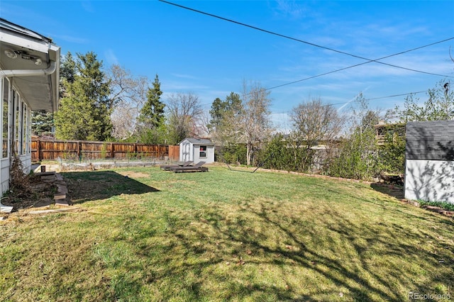 view of yard featuring a storage unit, an outbuilding, and a fenced backyard