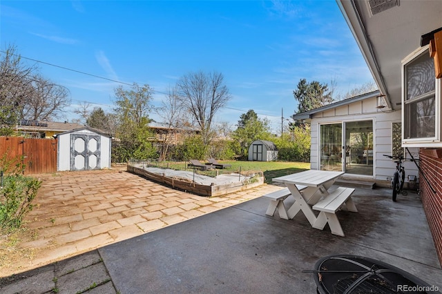 view of patio with an outdoor structure, fence, outdoor dining space, and a storage shed