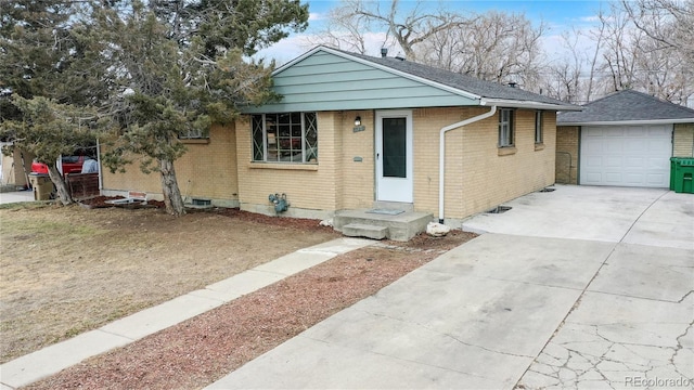 view of front of home featuring an outbuilding, driveway, and brick siding