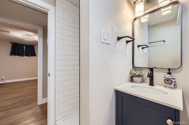 bathroom featuring tiled shower, vanity, and wood-type flooring