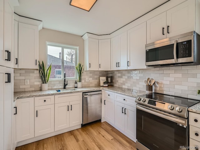 kitchen with sink, white cabinets, tasteful backsplash, and appliances with stainless steel finishes