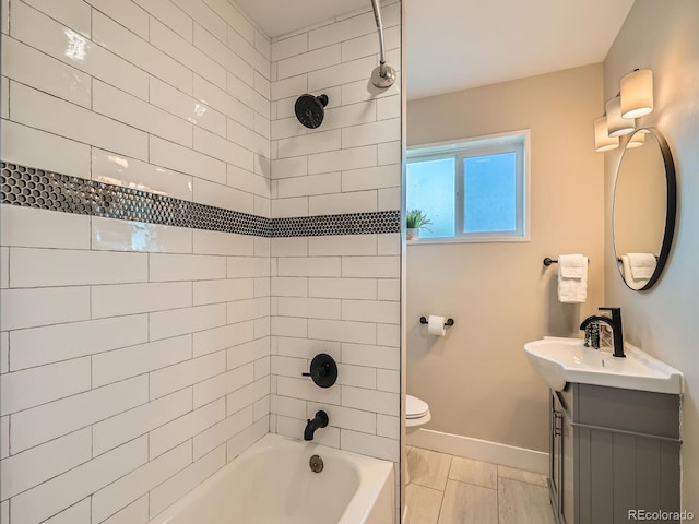 full bathroom featuring vanity, tiled shower / bath combo, and toilet