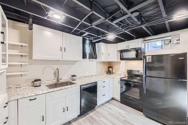 kitchen featuring black appliances, light hardwood / wood-style floors, light stone countertops, white cabinets, and sink