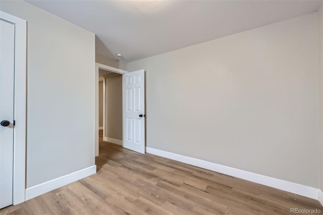 unfurnished bedroom featuring vaulted ceiling, light wood-type flooring, and a closet