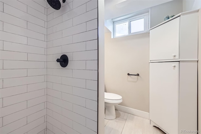 bathroom featuring a tile shower and toilet