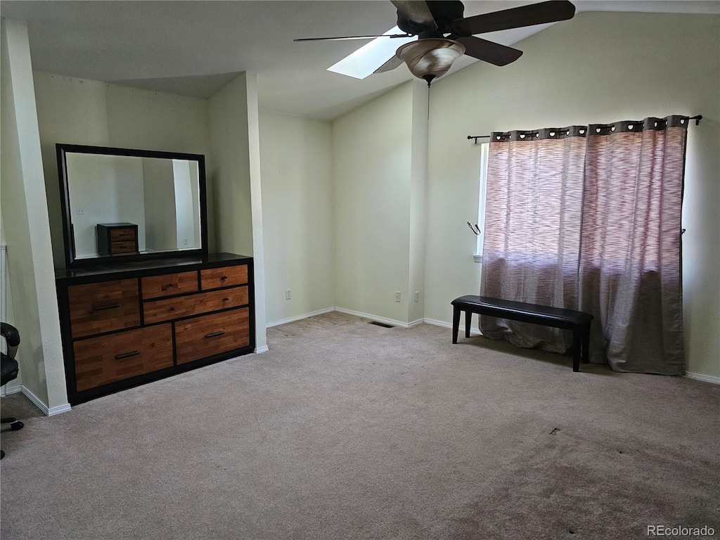 bedroom featuring ceiling fan, visible vents, baseboards, lofted ceiling with skylight, and carpet