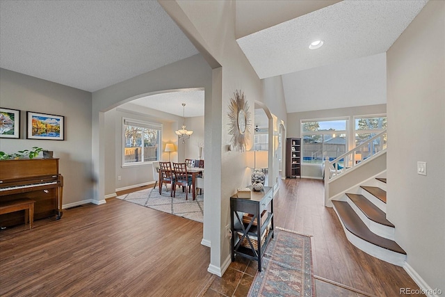 entrance foyer featuring an inviting chandelier, hardwood / wood-style floors, vaulted ceiling, and a textured ceiling