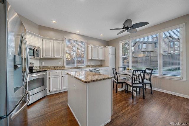 kitchen with sink, white cabinetry, stainless steel appliances, dark hardwood / wood-style floors, and a center island