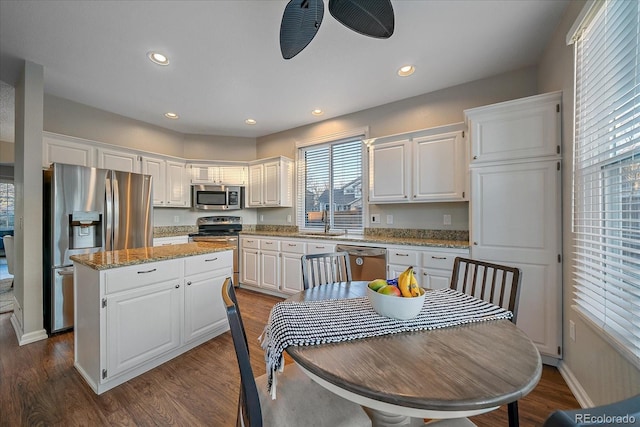 kitchen with sink, appliances with stainless steel finishes, white cabinetry, dark hardwood / wood-style floors, and a center island