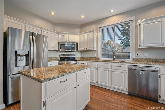 kitchen with sink, white cabinetry, light stone counters, appliances with stainless steel finishes, and a kitchen island