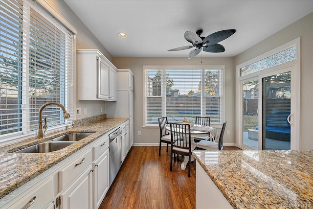 kitchen with sink, stainless steel dishwasher, white cabinets, and light stone counters