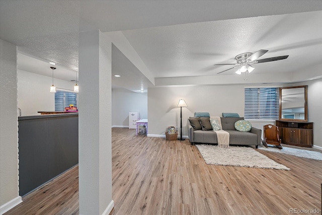 living room with ceiling fan, hardwood / wood-style floors, and a textured ceiling