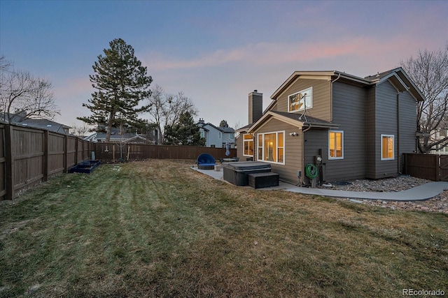 back house at dusk featuring a yard and a jacuzzi