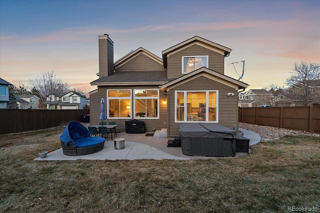 back house at dusk with a lawn and a patio