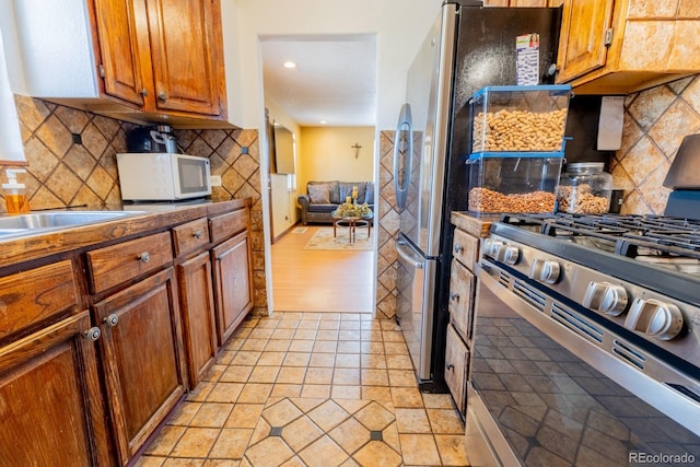 3021 Grape St, Denver, CO 80207 - kitchen with stainless steel range with gas cooktop, white microwave, decorative backsplash, brown cabinets, and recessed lighting