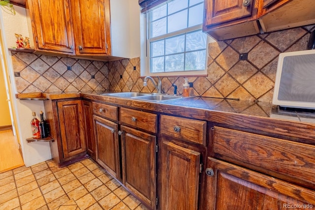 3021 Grape St, Denver, CO 80207 - kitchen featuring a sink, tasteful backsplash, dark countertops, brown cabinetry, and light stone finish floors