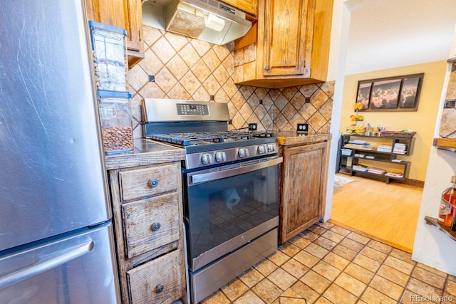 3021 Grape St, Denver, CO 80207 - kitchen with stainless steel appliances, under cabinet range hood, tasteful backsplash, and brown cabinets
