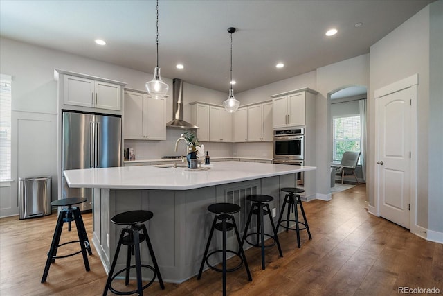 5663 W 96th Ave, Westminster, CO 80020 - kitchen featuring stainless steel appliances, wall chimney range hood, light countertops, a kitchen breakfast bar, and a large island