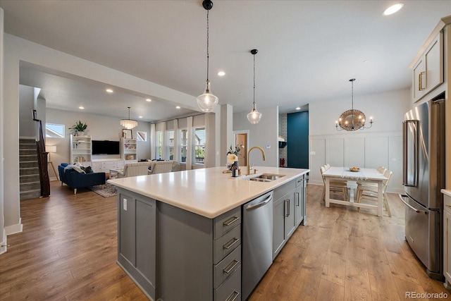 5663 W 96th Ave, Westminster, CO 80020 - kitchen featuring stainless steel appliances, gray cabinets, light countertops, light wood-style floors, and an island with sink