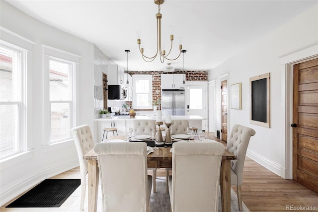 dining space featuring light wood-type flooring, baseboards, a healthy amount of sunlight, and visible vents