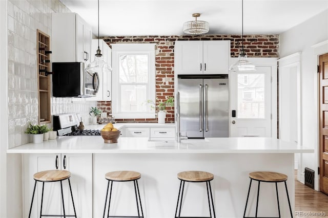 kitchen featuring a breakfast bar area, a peninsula, white cabinets, and appliances with stainless steel finishes