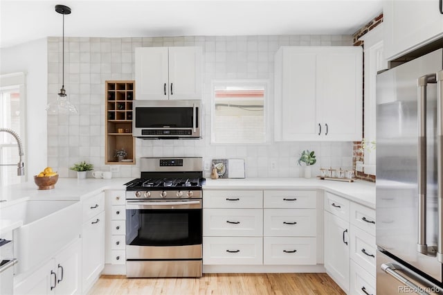 kitchen featuring backsplash, appliances with stainless steel finishes, light countertops, a sink, and white cabinets