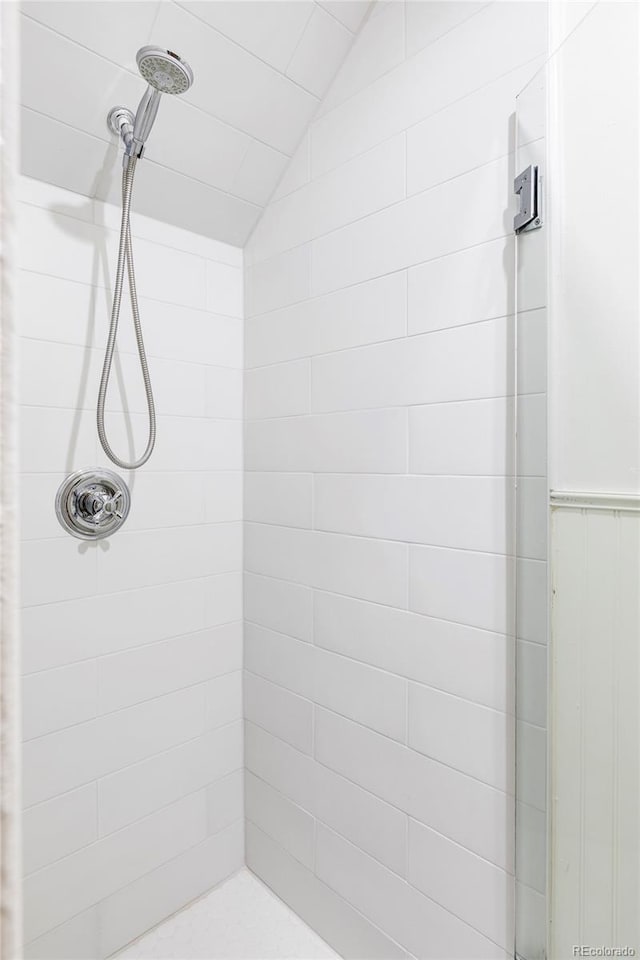 bathroom featuring a tile shower and lofted ceiling
