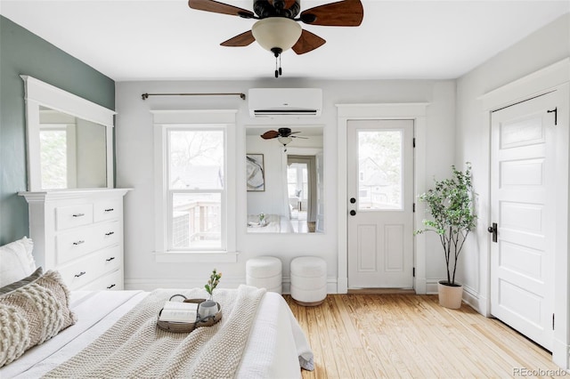 bedroom with an AC wall unit, a ceiling fan, and light wood finished floors