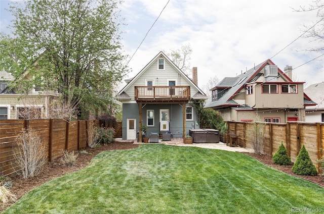 back of house featuring a hot tub, a yard, and a fenced backyard