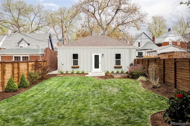rear view of property featuring a fenced backyard, board and batten siding, and roof with shingles