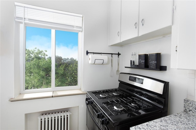 85 N Grant St Unit 27, Denver, CO 80203 - kitchen with range with gas stovetop, radiator heating unit, white cabinetry, and healthy amount of natural light