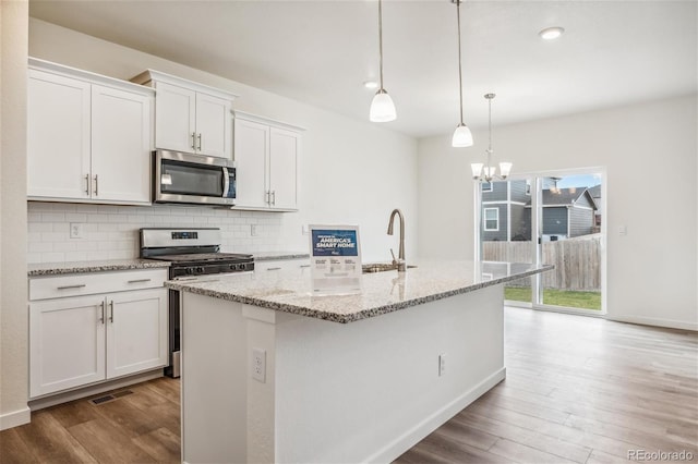 27684 E Byers Ave, Aurora, CO 80018 - kitchen with appliances with stainless steel finishes, a sink, wood finished floors, backsplash, and a kitchen island with sink