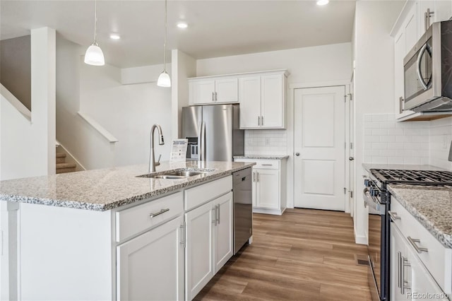 27684 E Byers Ave, Aurora, CO 80018 - kitchen featuring appliances with stainless steel finishes, a sink, white cabinets, light wood-type flooring, and recessed lighting