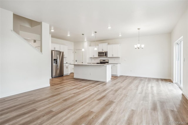 27684 E Byers Ave, Aurora, CO 80018 - kitchen featuring appliances with stainless steel finishes, open floor plan, a sink, a chandelier, and light wood finished floors