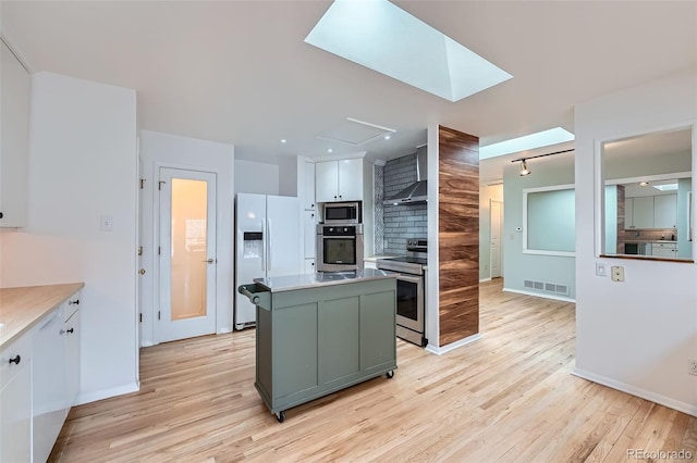 8095 E Lehigh Ave, Denver, CO 80237 - kitchen featuring stainless steel appliances, light wood-style floors, wall chimney exhaust hood, and a kitchen island