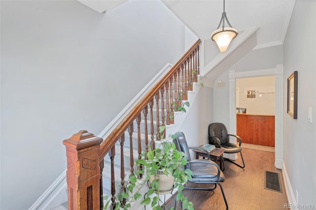 stairway with wood-type flooring and ornamental molding