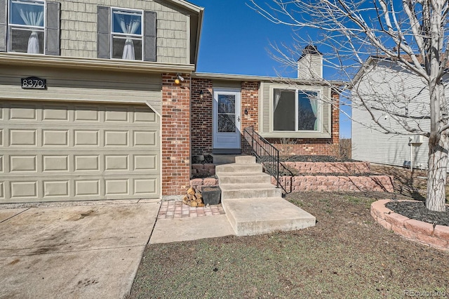 entrance to property with an attached garage, brick siding, driveway, and a chimney