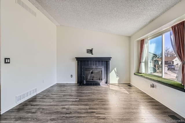 unfurnished living room with visible vents, a fireplace, lofted ceiling, and wood finished floors