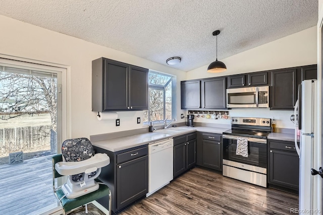 kitchen featuring a sink, stainless steel appliances, light countertops, lofted ceiling, and dark wood-style flooring