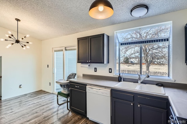 kitchen with dishwasher, wood finished floors, a notable chandelier, a textured ceiling, and a sink