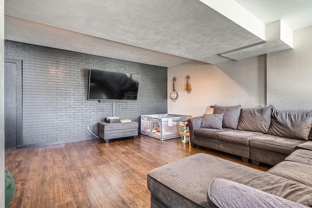 living room with a textured ceiling, wood finished floors, and brick wall