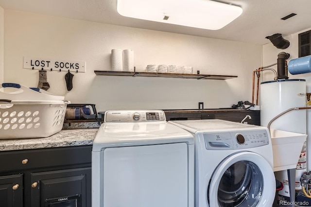 laundry area with cabinet space, independent washer and dryer, and water heater