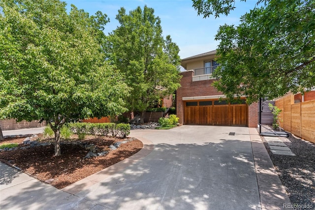 350 Holly St, Denver, CO 80220 - view of property hidden behind natural elements with brick siding, driveway, an attached garage, and a balcony