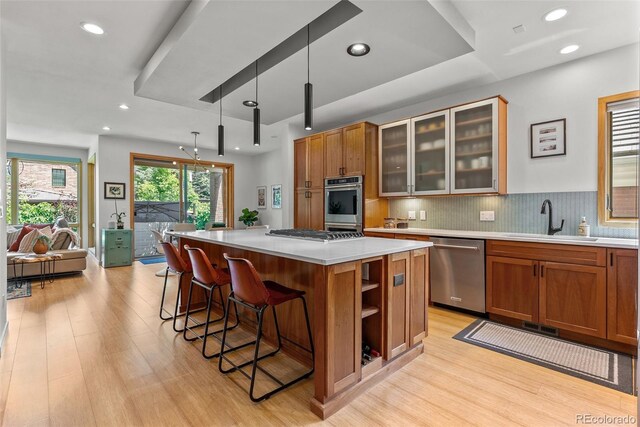 350 Holly St, Denver, CO 80220 - kitchen featuring appliances with stainless steel finishes, a sink, a center island, brown cabinetry, and light countertops