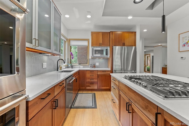350 Holly St, Denver, CO 80220 - kitchen with appliances with stainless steel finishes, a sink, light wood-style flooring, tasteful backsplash, and brown cabinets
