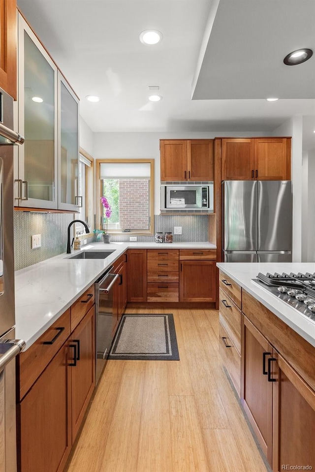 350 Holly St, Denver, CO 80220 - kitchen featuring stainless steel appliances, a sink, light wood finished floors, light countertops, and brown cabinetry