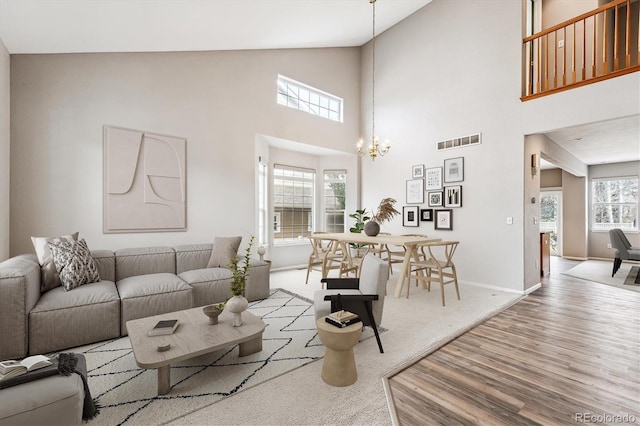 living room featuring an inviting chandelier, a high ceiling, and light wood-type flooring